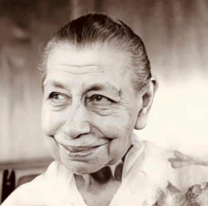 A black and white photograph of The Mother. She is gazing at something off camera, with a small, sweet smile.